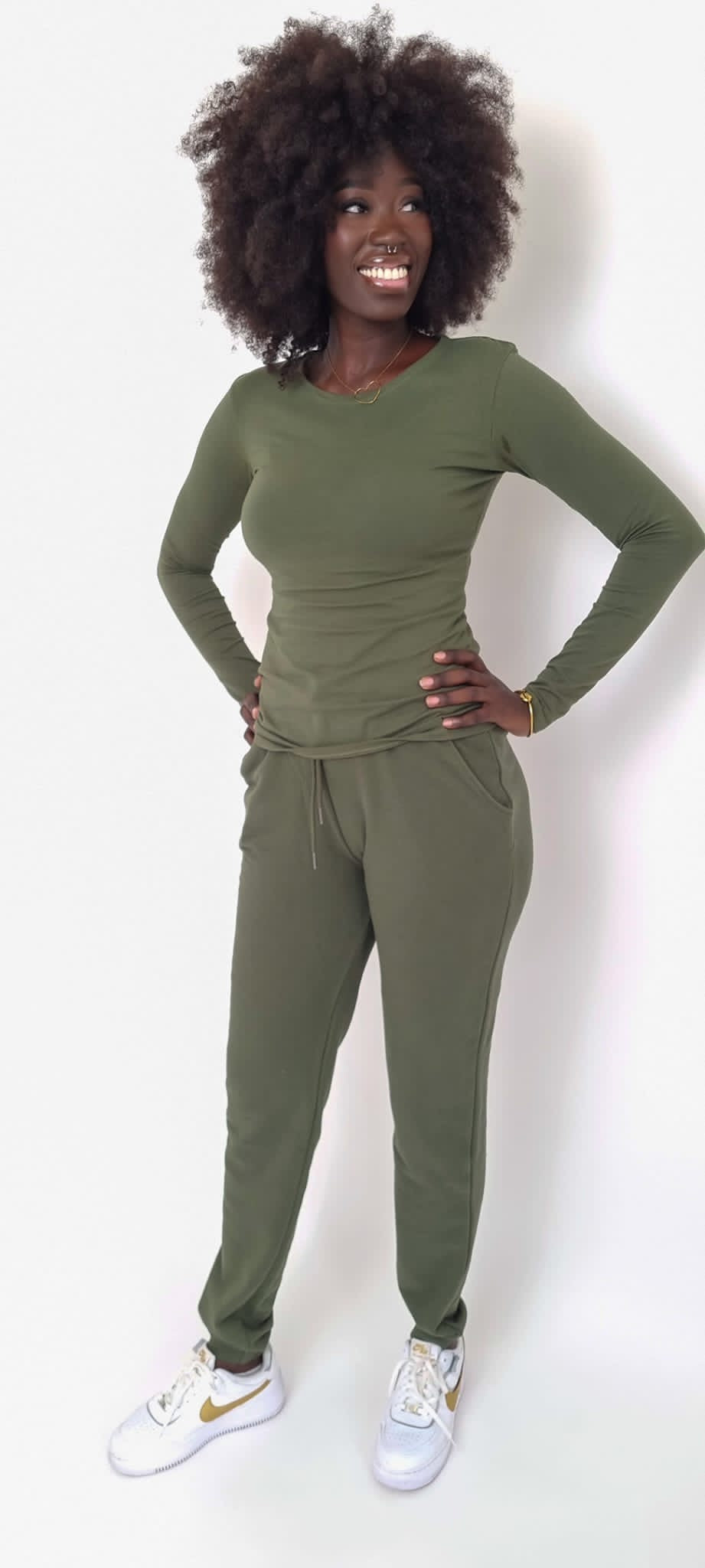 Tall woman wearing an extended sleeve top and joggers.