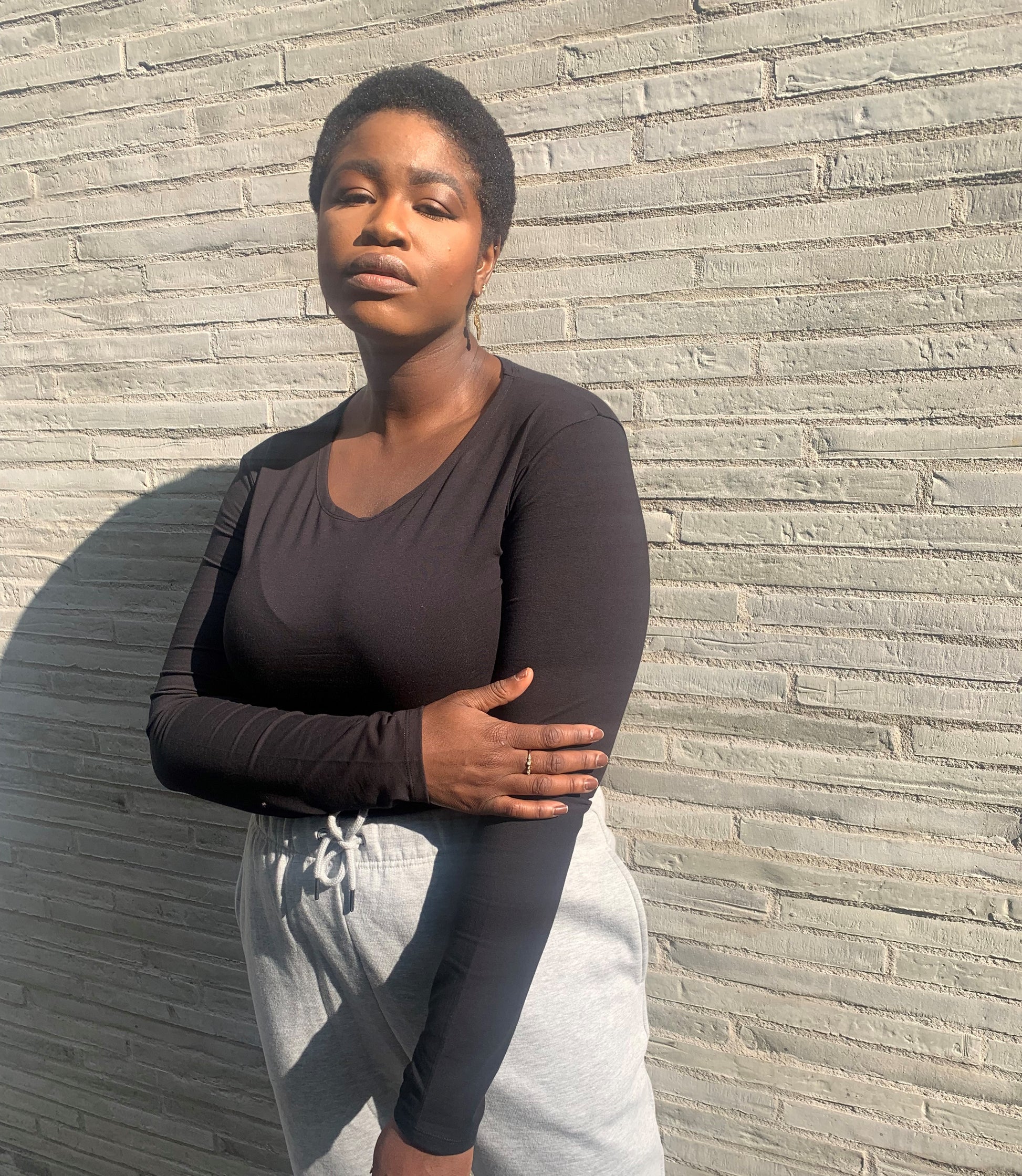 Tall woman pairing long sleeve black top with grey joggers outdoors